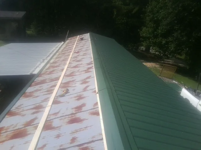 Old rusted panels beside newly installed green metal roofing — Wind Damage Roof Repair by Roofing Brothers in Windsor Locks