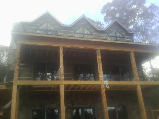 Dormers and porch framing on a large log home under construction — Roof Coating work by our crew in Windsor Locks