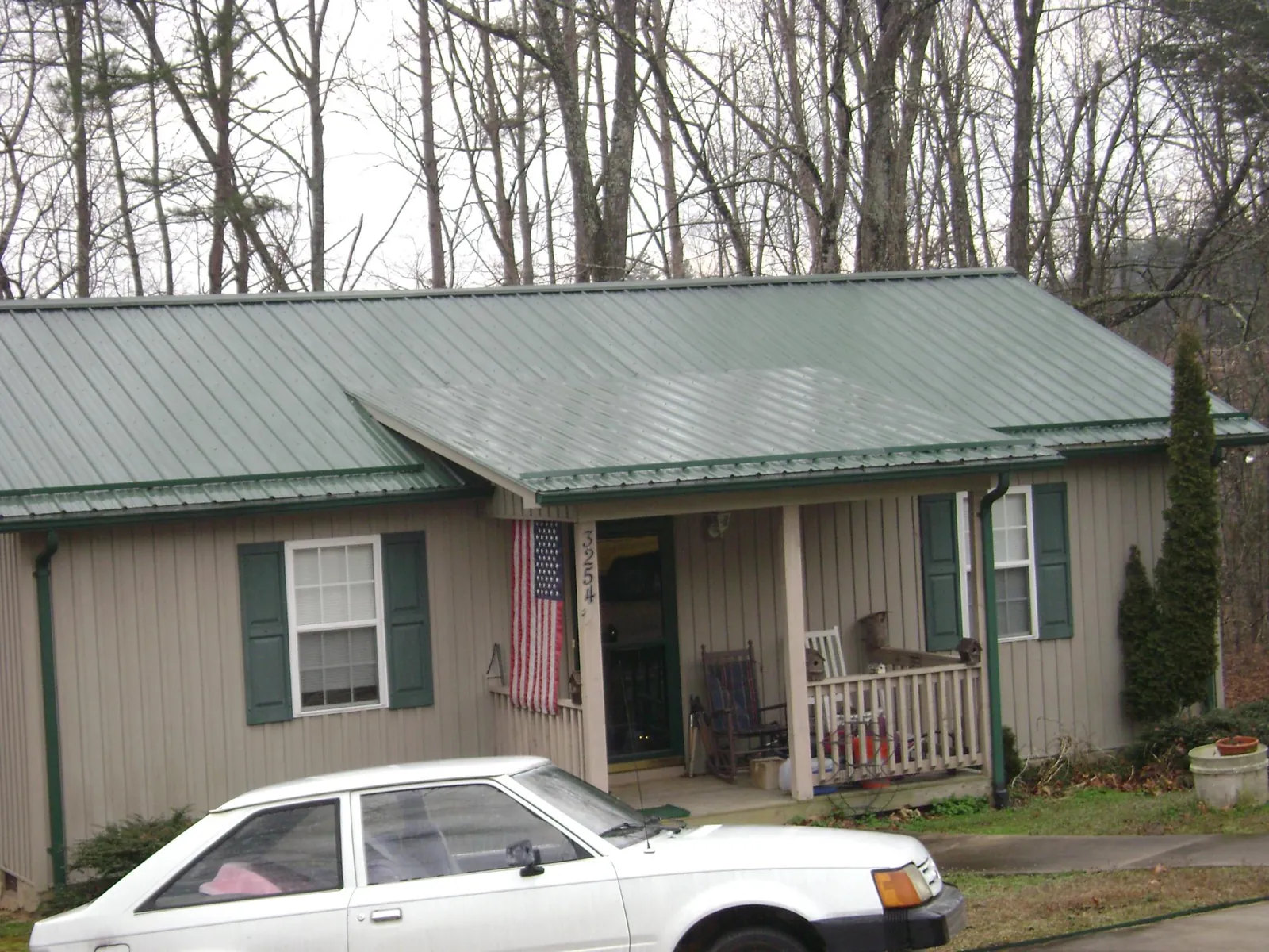 Green metal roof and front porch on a tan sided cottage in Windsor Locks
