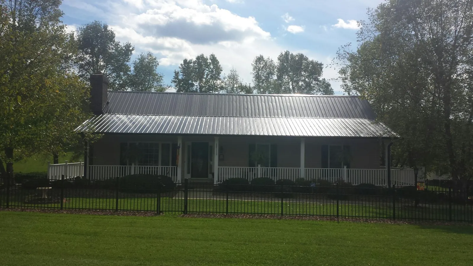 Gray metal roof on a brick ranch with a full width front porch — Gutter Guard Installation work by our crew in Windsor Locks